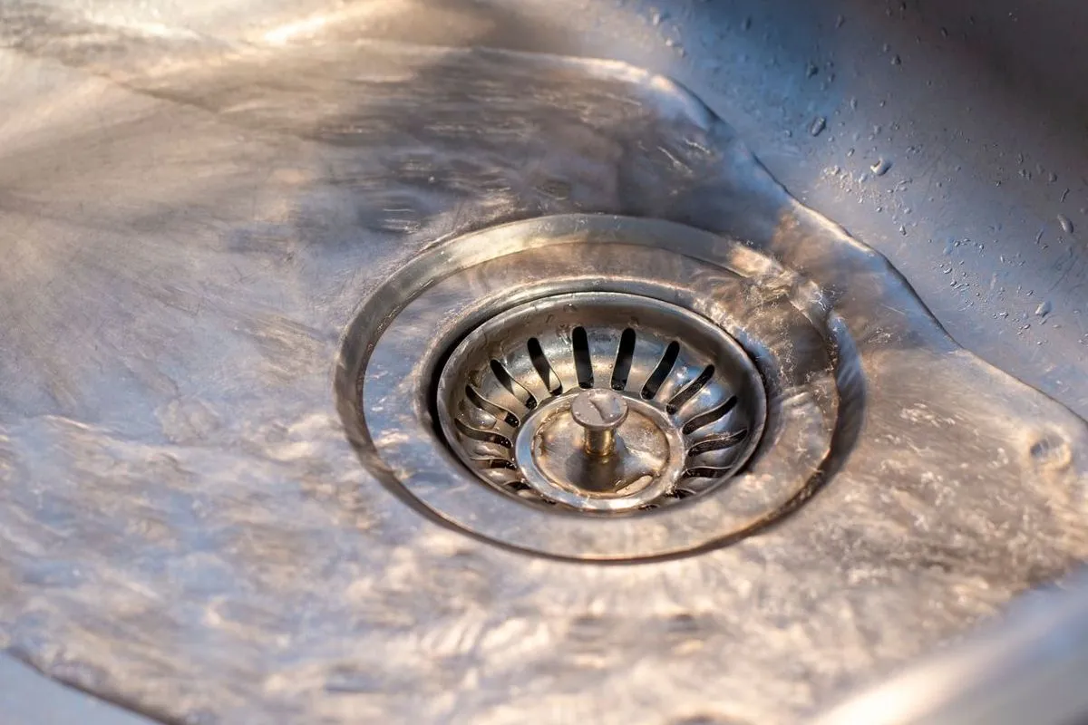 A close-up image showing a shiny stainless steel kitchen sink drain