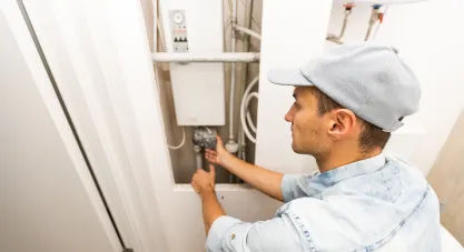 A technician working on a wall-mounted boiler system