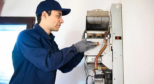 A technician carefully working on a furnace with a screwdriver