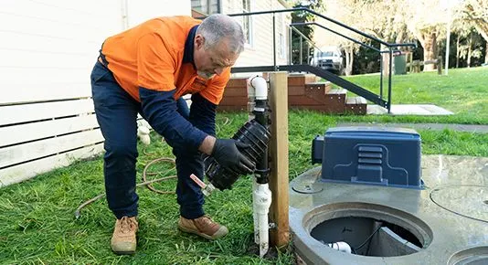 A First Service technician performing outdoor septic system maintenance