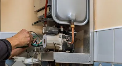 A technician actively working on the internal components of a wall-mounted water heater