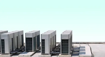 Multiple large outdoor multi-zone HVAC units neatly installed in rows on a building's rooftop under a clear sky