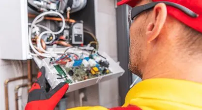 A technician examining the open internal components and circuit board of a wall-mounted heating unit